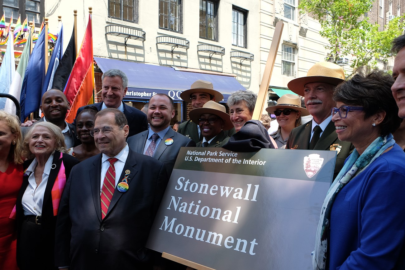 People gathered around a plaque that reads 'Stonewall National Monument'