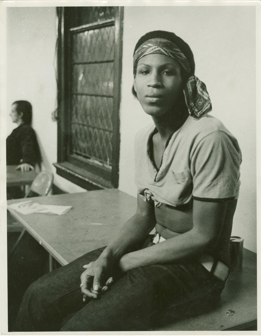 Zazu Nova, a black transgender woman, sits on top of a table at a Gay Liberation Front meeting in 1970.